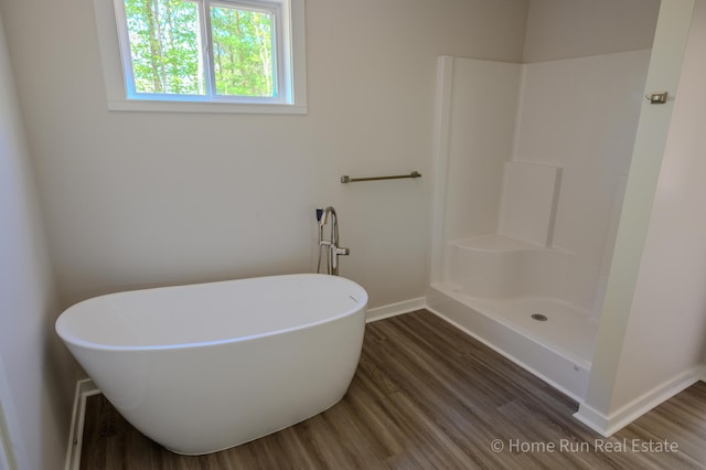 full bathroom with wood finished floors, baseboards, a soaking tub, and a shower