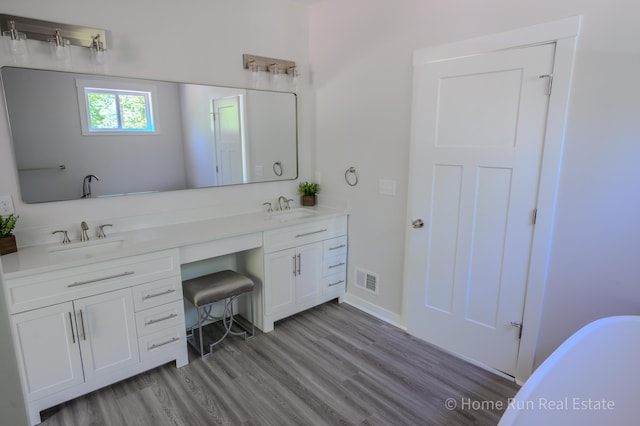 bathroom with wood finished floors, double vanity, and baseboards