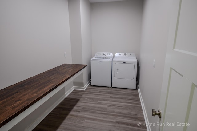 washroom with washing machine and dryer, baseboards, and wood finished floors
