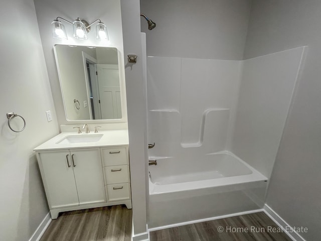 bathroom with wood finished floors, baseboards, bathing tub / shower combination, and vanity