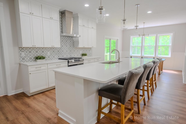 8828 Division Ave S, Byron Center, MI 49315 - kitchen featuring a sink, wall chimney exhaust hood, stainless steel range with gas stovetop, light wood finished floors, and recessed lighting