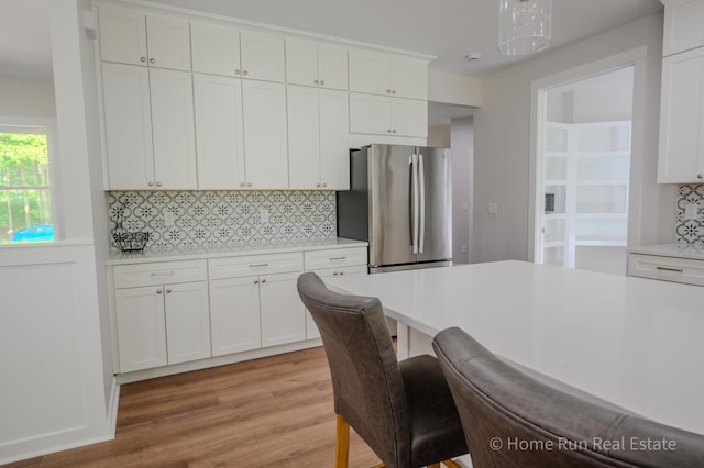 8828 Division Ave S, Byron Center, MI 49315 - kitchen featuring freestanding refrigerator, light countertops, light wood-style flooring, decorative backsplash, and white cabinets