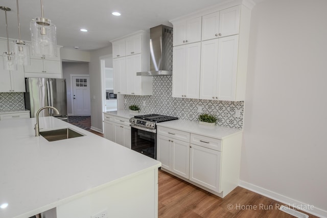8828 Division Ave S, Byron Center, MI 49315 - kitchen featuring a sink, appliances with stainless steel finishes, wall chimney exhaust hood, tasteful backsplash, and light wood-style flooring