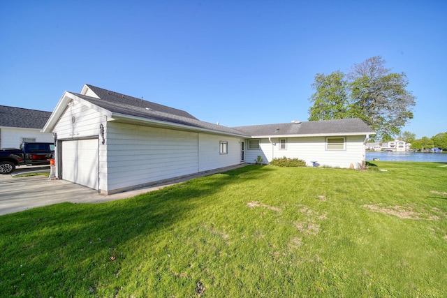 555 S Lakeside Dr, Michigan Center, MI 49254 - rear view of house with a garage, a lawn, and a water view