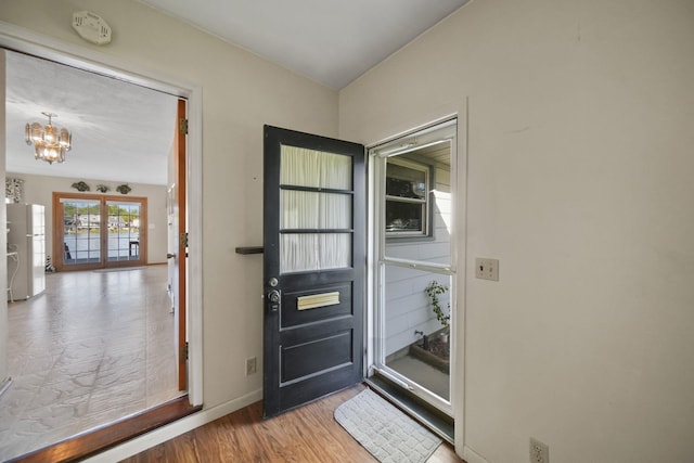 555 S Lakeside Dr, Michigan Center, MI 49254 - doorway featuring a chandelier, wood finished floors, and baseboards