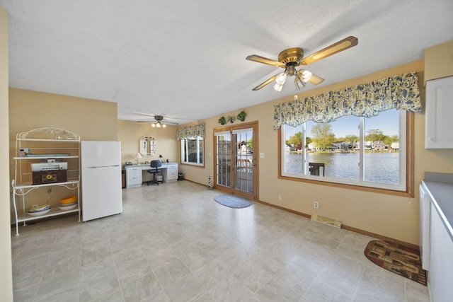 555 S Lakeside Dr, Michigan Center, MI 49254 - kitchen with freestanding refrigerator, a ceiling fan, an office area, white cabinets, and baseboards