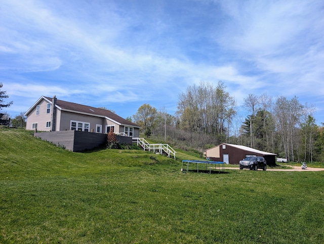 view of grassy yard with a detached garage and an outbuilding