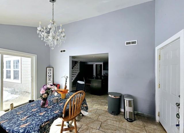 dining area with stairway, a chandelier, a high ceiling, baseboards, and light stone finish floors