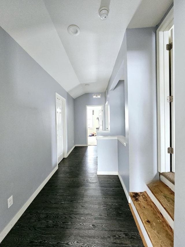 hallway with baseboards, lofted ceiling, and dark wood-type flooring