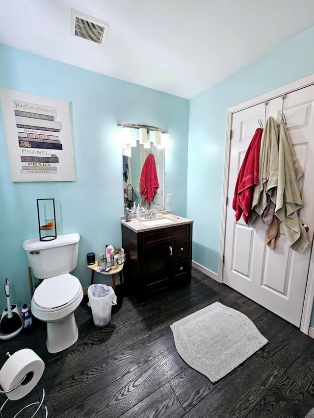 bathroom with wood finished floors, vanity, toilet, and baseboards