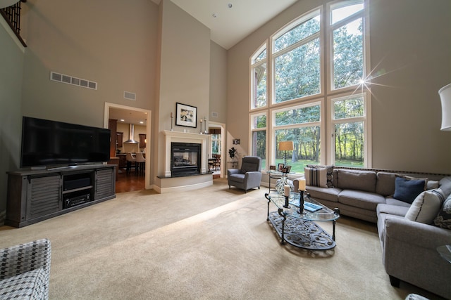 8307 Granite Ct, Dexter, MI 48130 - living room with high vaulted ceiling, carpet flooring, healthy amount of natural light, a glass covered fireplace, and baseboards