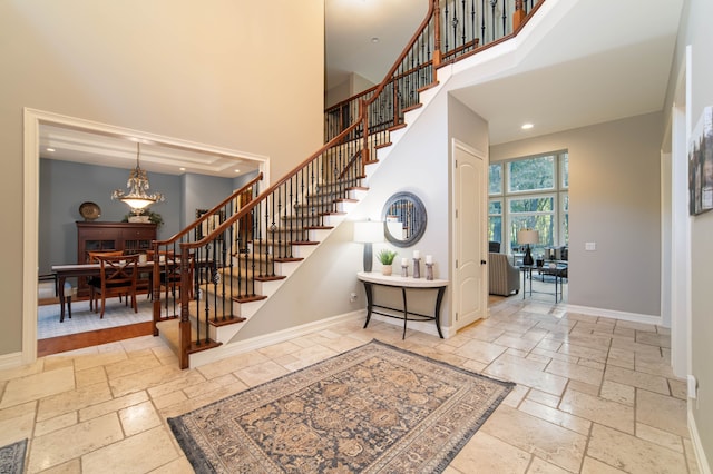 8307 Granite Ct, Dexter, MI 48130 - stairway featuring stone tile flooring, a towering ceiling, baseboards, a chandelier, and recessed lighting