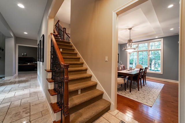 8307 Granite Ct, Dexter, MI 48130 - stairway featuring recessed lighting, baseboards, a tray ceiling, and a chandelier