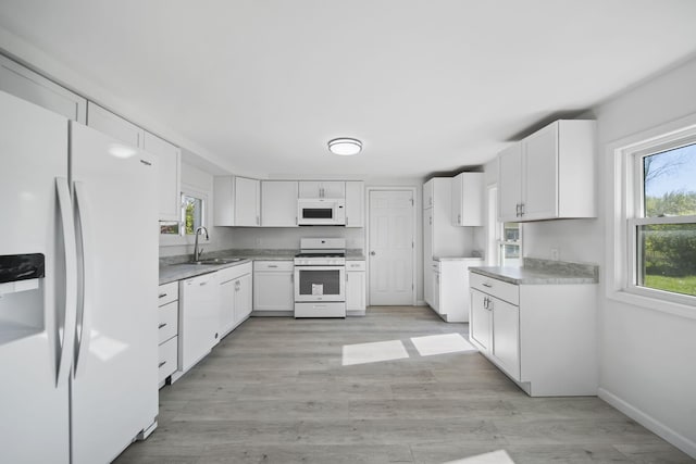 kitchen featuring white appliances, a sink, light wood-type flooring, white cabinets, and light countertops