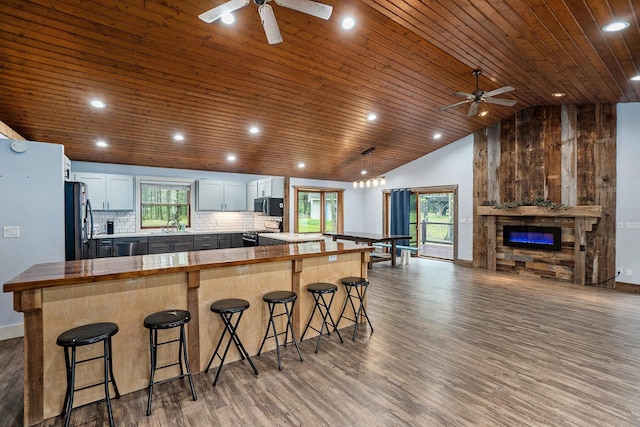 1977 E 40th St, White Cloud, MI 49349 - kitchen with ceiling fan, appliances with stainless steel finishes, wooden ceiling, a kitchen breakfast bar, and wood finished floors