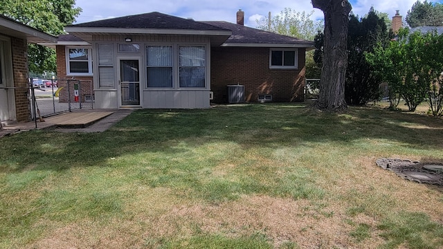 back of property featuring brick siding, a chimney, a lawn, and a shingled roof