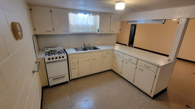 kitchen with white gas range oven, a sink, light countertops, light flooring, and white cabinets