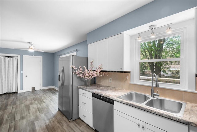 kitchen with stainless steel appliances, a sink, white cabinetry, and tasteful backsplash