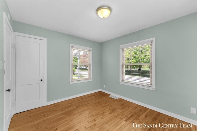 unfurnished bedroom with multiple windows, wood finished floors, and baseboards