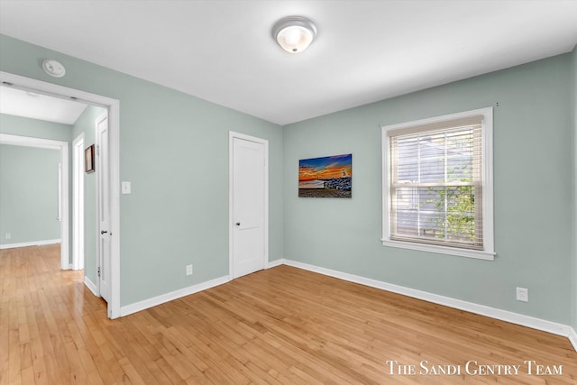 spare room featuring a smoke detector, light wood-style flooring, and baseboards