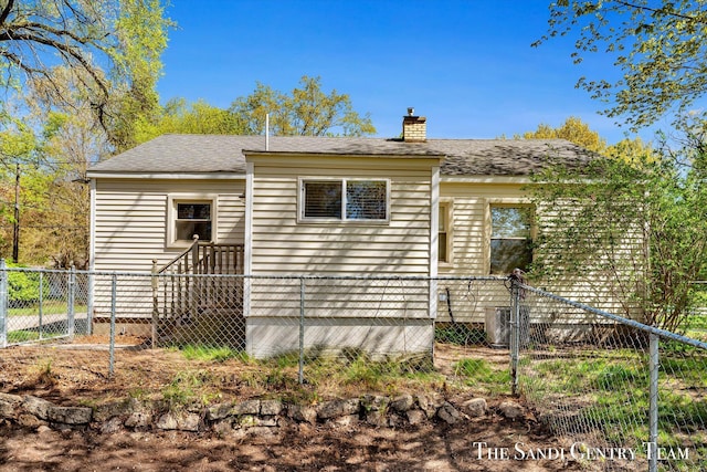 rear view of house featuring a chimney, fence, cooling unit, and roof with shingles
