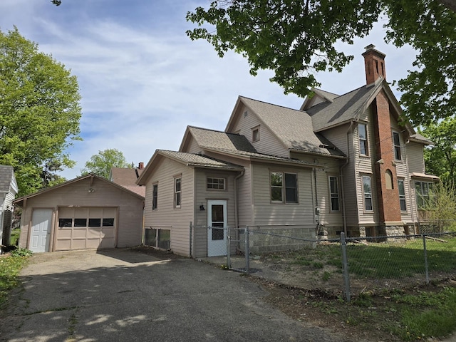 318 W King St, Owosso, MI 48867 - view of front of house with a garage, an outbuilding, a chimney, and asphalt driveway