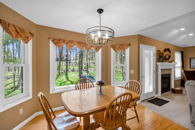9100 Boggie Dr Unit 159, Canadian Lakes, MI 49346 - dining space featuring a chandelier, healthy amount of natural light, light wood-style flooring, and a fireplace