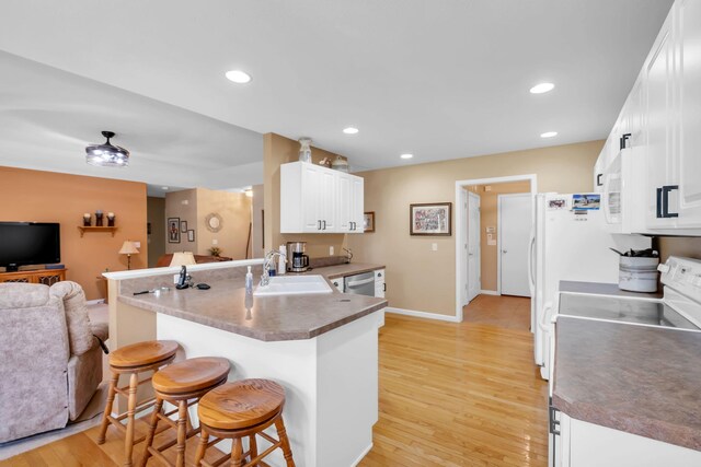 9100 Boggie Dr Unit 159, Canadian Lakes, MI 49346 - kitchen with a sink, open floor plan, a kitchen breakfast bar, a peninsula, and white cabinets
