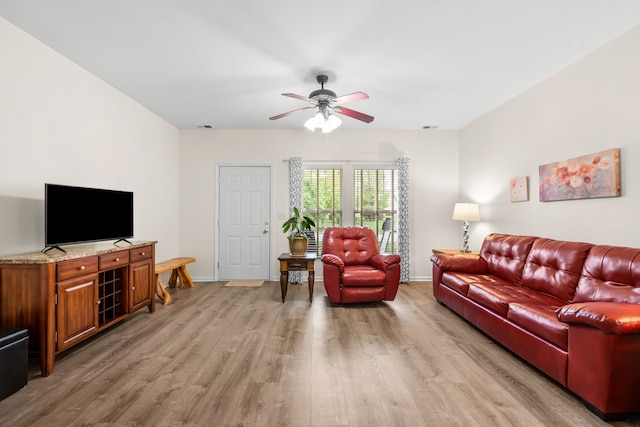living room with light wood finished floors, a ceiling fan, and baseboards