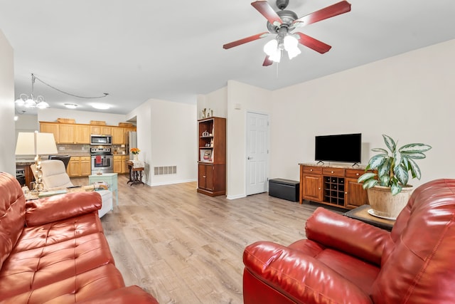 living area with a ceiling fan, light wood-style floors, baseboards, and a chandelier