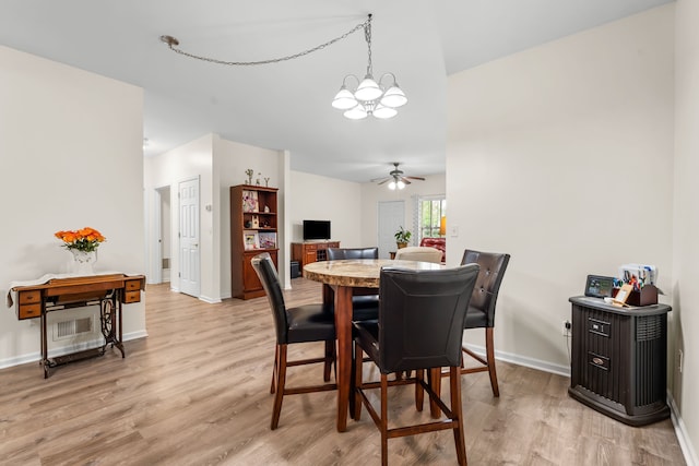 dining room with a chandelier, light wood-style flooring, a ceiling fan, and baseboards