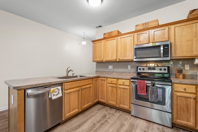 kitchen with stainless steel appliances, a sink, a peninsula, and backsplash