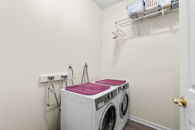 clothes washing area featuring washing machine and dryer, baseboards, and dark wood-style floors