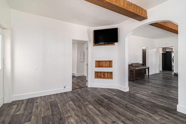 601 N Rath Ave, Ludington, MI 49431 - unfurnished living room featuring dark wood-type flooring, beam ceiling, arched walkways, and baseboards