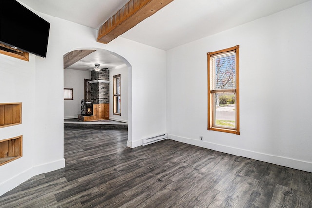 601 N Rath Ave, Ludington, MI 49431 - unfurnished room featuring baseboard heating, dark wood-style floors, beamed ceiling, baseboards, and arched walkways