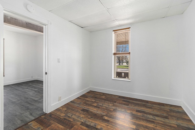 601 N Rath Ave, Ludington, MI 49431 - unfurnished room featuring dark wood-style flooring, baseboards, and a paneled ceiling