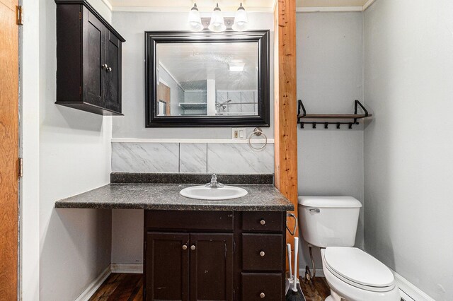 601 N Rath Ave, Ludington, MI 49431 - bathroom with toilet, vanity, wood finished floors, baseboards, and backsplash