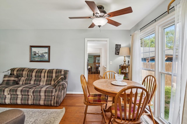 dining area with wood finished floors, a ceiling fan, and baseboards