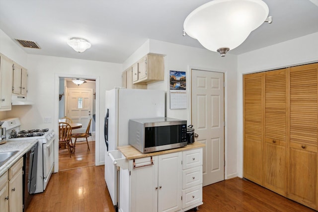 kitchen featuring stainless steel microwave, white gas stove, under cabinet range hood, light countertops, and light wood-style floors