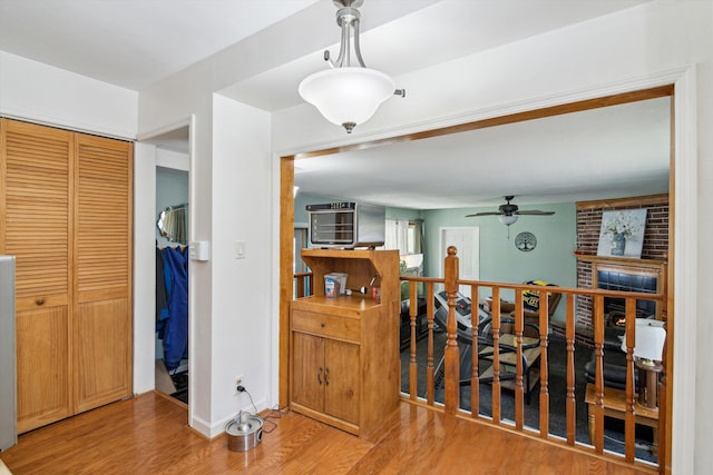 hallway featuring wood finished floors, an upstairs landing, and baseboards