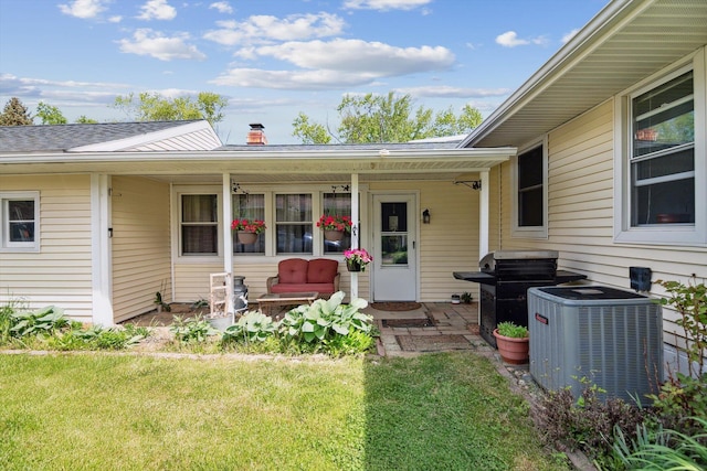 entrance to property with central AC, a lawn, a chimney, and a porch