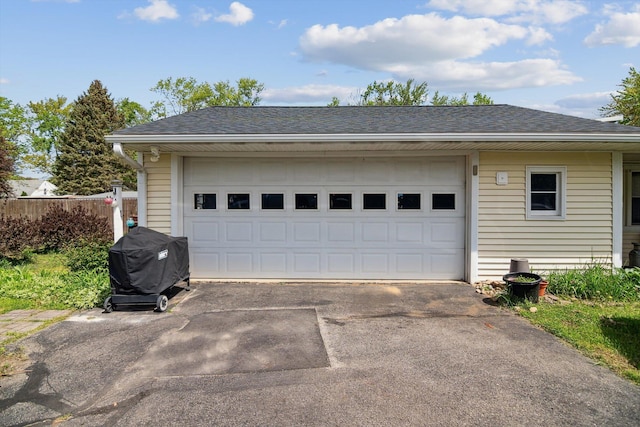 garage with asphalt driveway and fence