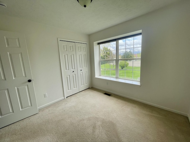 unfurnished bedroom with baseboards, carpet, and a closet