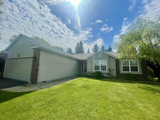 view of front of house featuring brick siding, a garage, asphalt driveway, and a front lawn