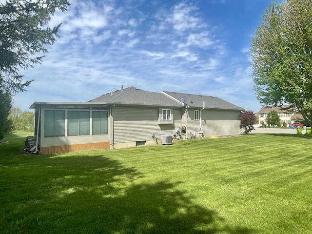 rear view of house with central air condition unit, a yard, and a sunroom