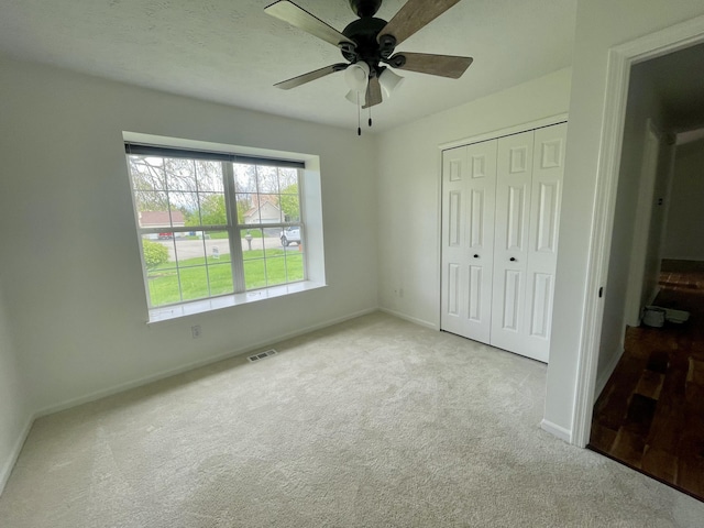 unfurnished bedroom featuring carpet flooring, a closet, baseboards, and a ceiling fan