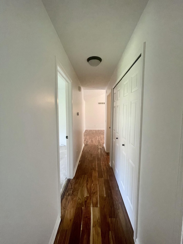 hall featuring dark wood-type flooring and baseboards