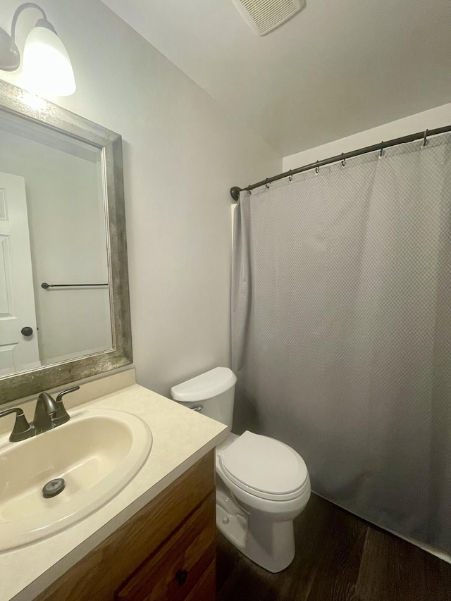 bathroom featuring toilet, wood finished floors, vanity, and curtained shower