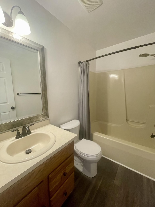 full bathroom with wood finished floors, shower / bathtub combination with curtain, vanity, and toilet