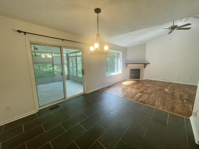 unfurnished living room featuring ceiling fan, a textured ceiling, baseboards, dark tile patterned floors, and vaulted ceiling